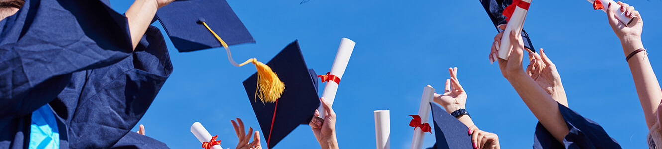 College graduates tossing their graduation hats up in the airt