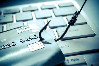 A fish hook catching a credit card on top of a laptop