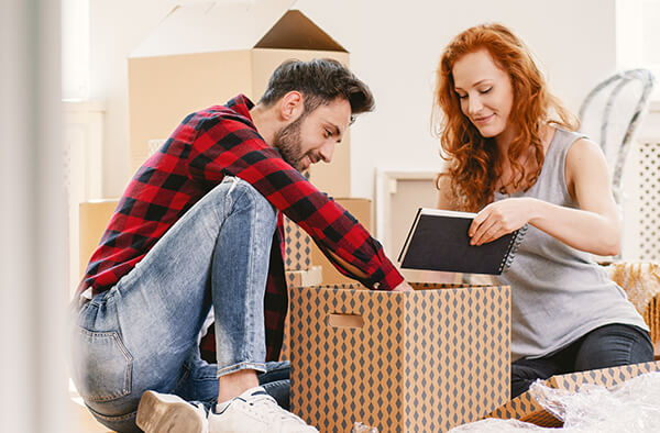 Young couple unpacking a box after moving in their new home