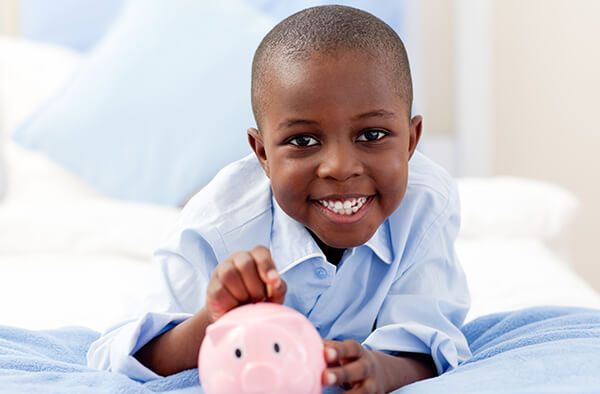 Young boy putting money in a piggy bank